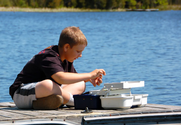child on dock with fishing tackle